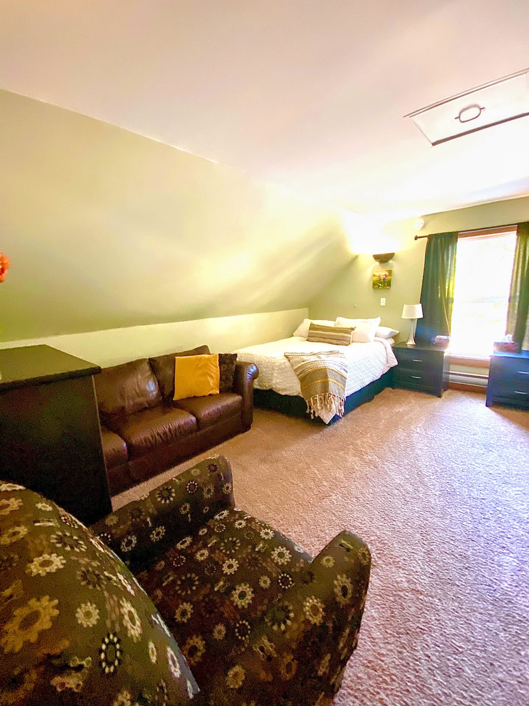 A second bedroom with a queen bed, sofa and garden window