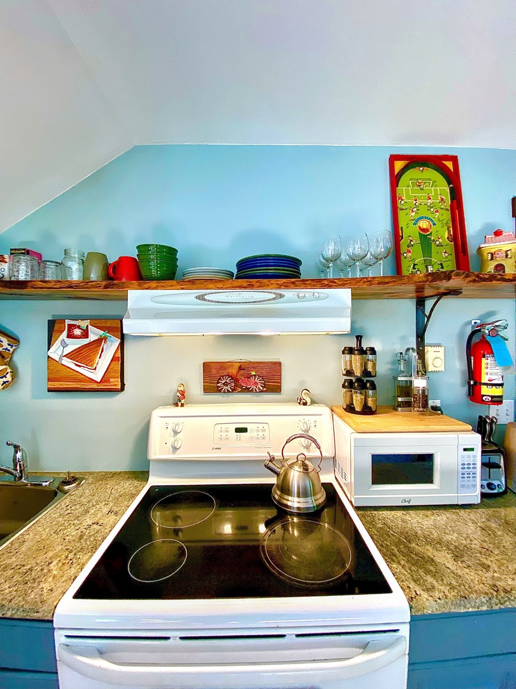 Range, kettle and stacked dishes on the live-edge shelf